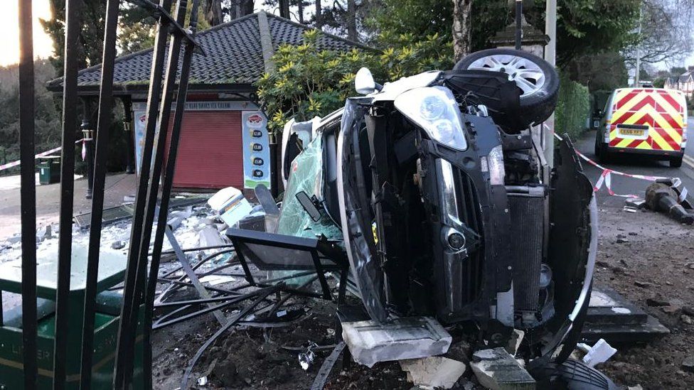 Car on its side at damaged park entrance