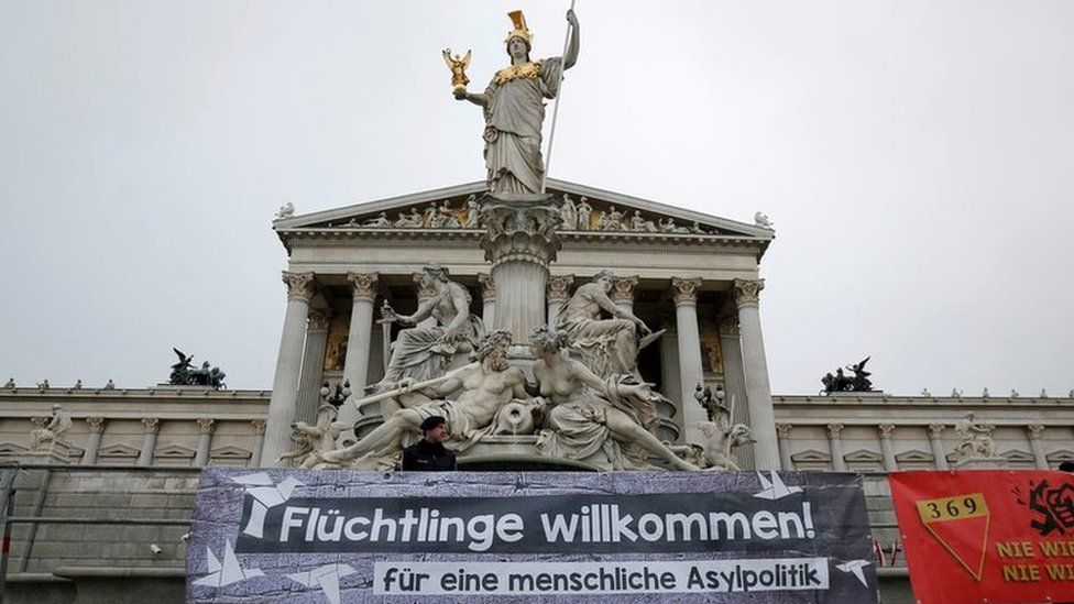 Austrian police officers stand behind a banner in front of the Parliament in Vienna