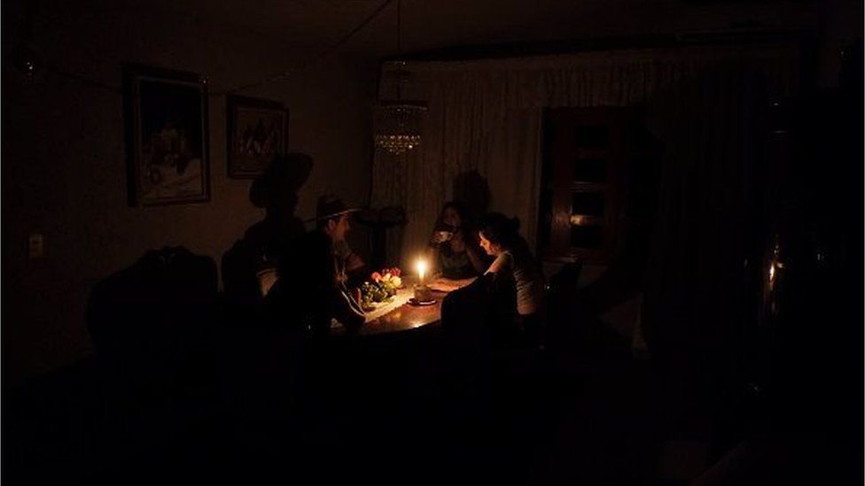 A family sit at a candle lit table in the state of Barinas, 600 km west of Caracas on April 25, 2016