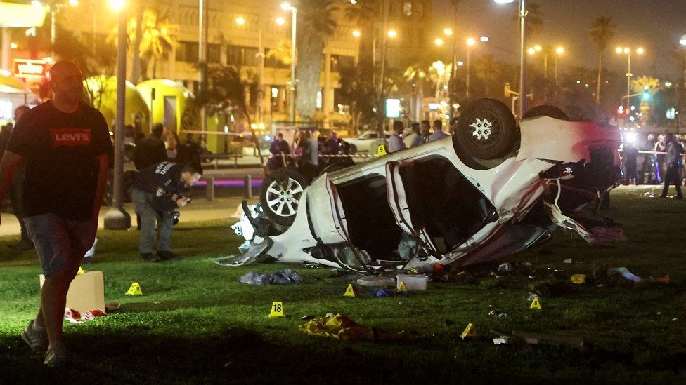 The aftermath of a car ramming attack on the beachside promenade in Tel Aviv. A white car can be seen on its roof.