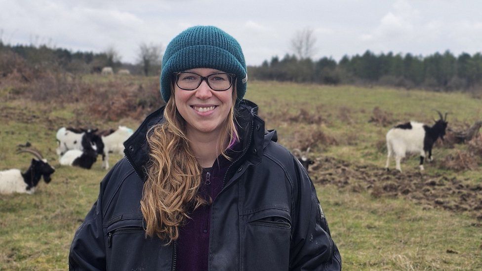 Laura Davey stood in a field surrounded by goats