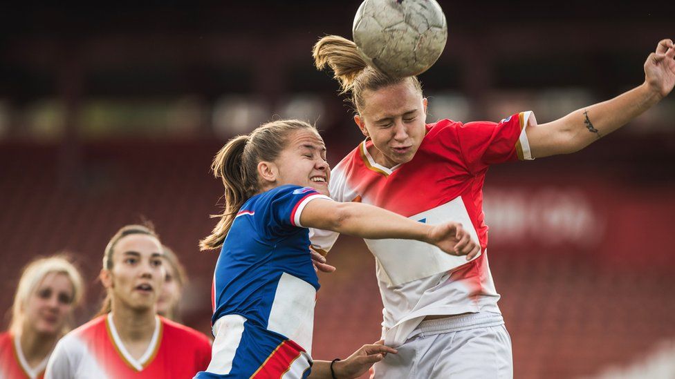 Female footballers heading the ball