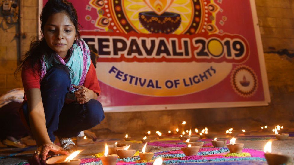 Woman lighting Diwali lamps
