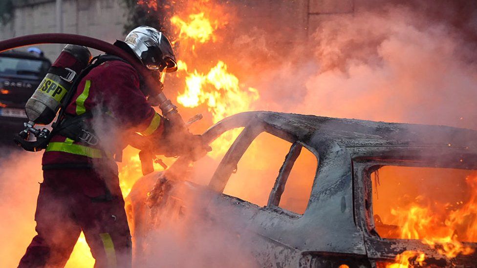 Ein Feuerwehrmann löscht ein Auto, das bei einer Demonstration am 27. Juni 2023 in Nanterre, Frankreich, in Brand geraten ist.