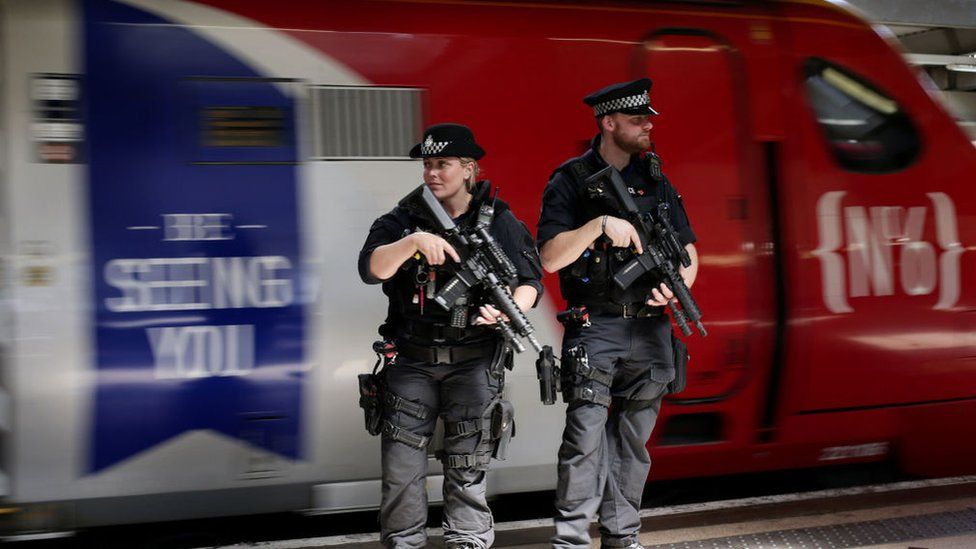 Armed British Transport Police Specialist Operations officers patrol on the platform before boarding a Virgin train to Birmingham New Street