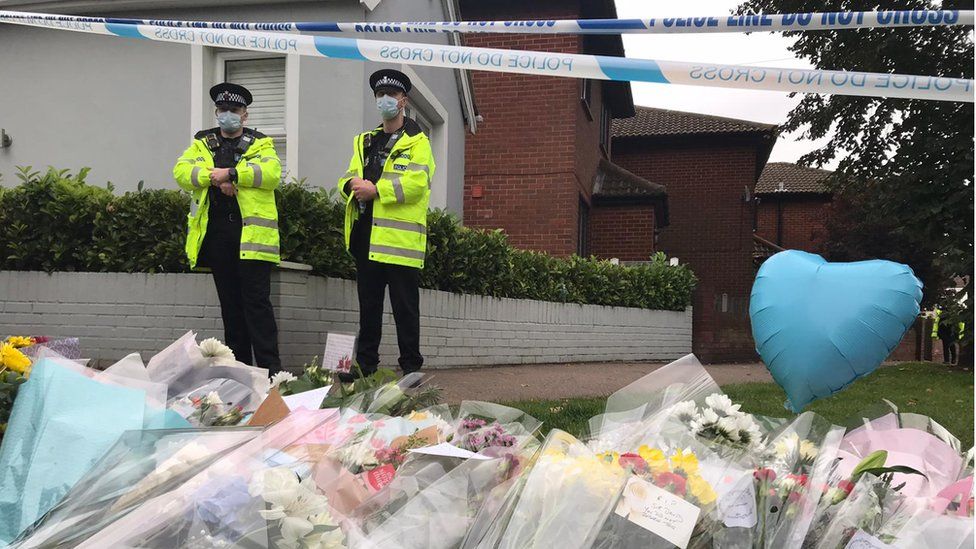 Police officers outside a cordon where tributes have been left