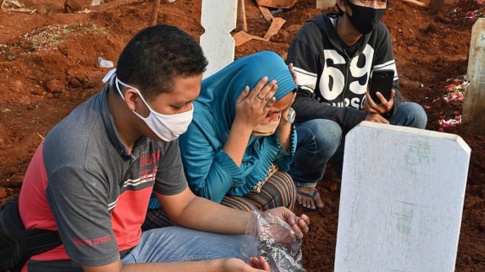Relatives pray for a loved one during a funeral for victims of Covid-19 in Jakarta, Indonesia