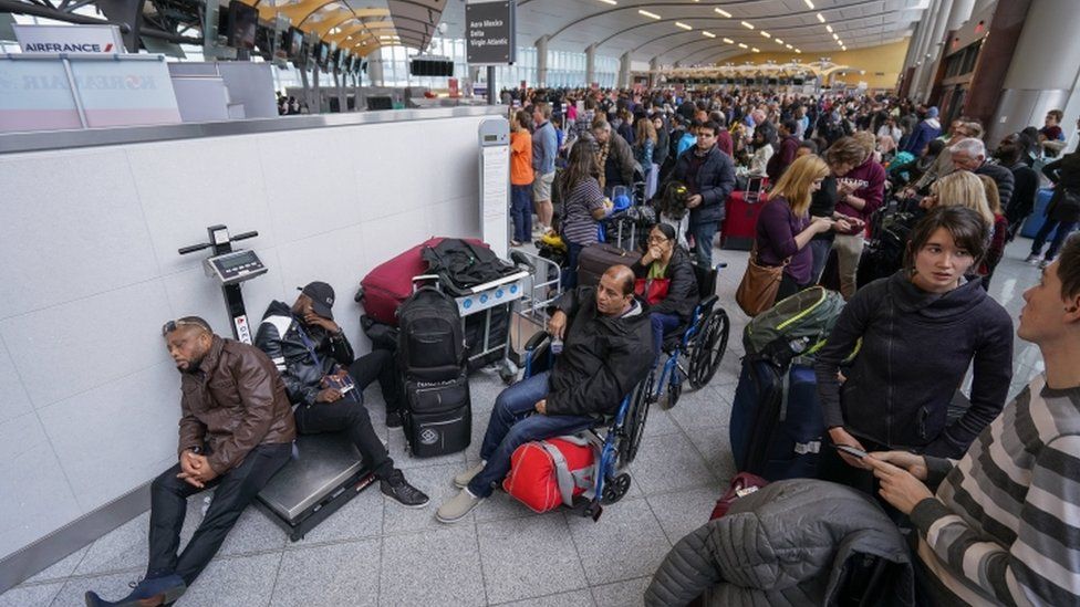 Passengers affected by widespread power outage sit in airport terminal and wait for updates