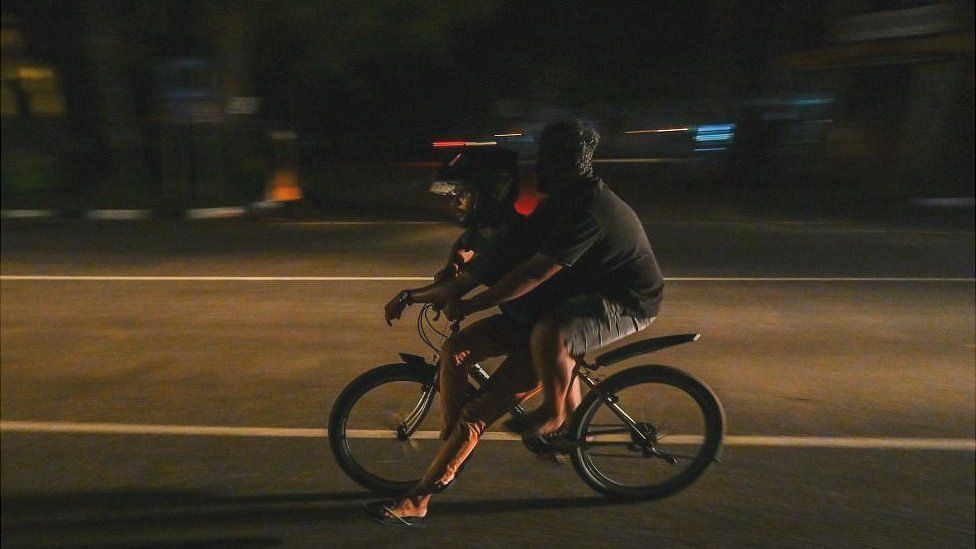 Youths riding a bicycle during a power cut in Galle, Sri Lanka