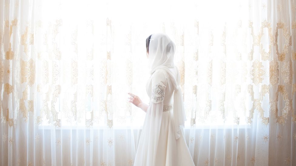 Woman in wedding dress looks out of window