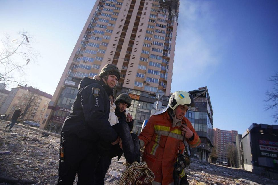 People evacuate a wounded person after an attack on a residential building during Russia's military intervention in Kyiv, Ukraine on February 26, 2022.