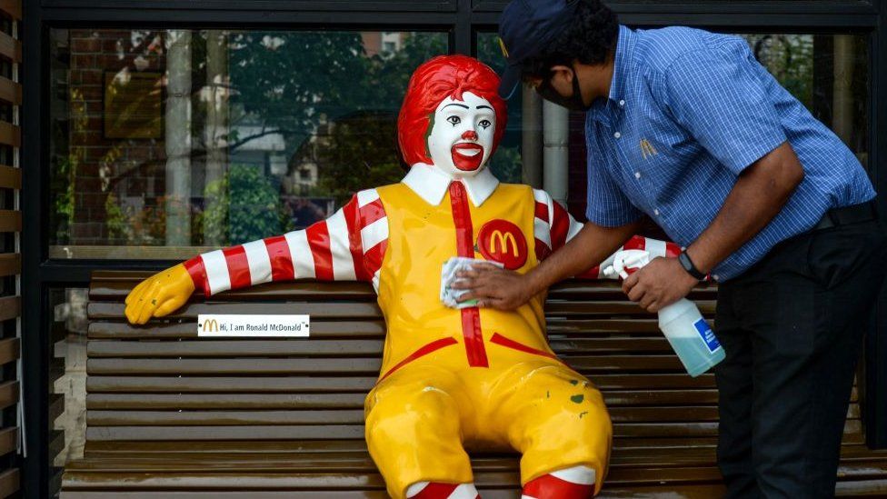A worker cleans the mascot of fast-food company McDonald's for the reopening of the outlet in Hyderabad on May 20.