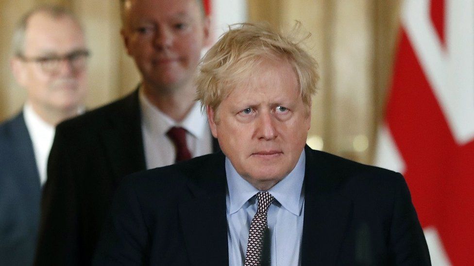 Prime Minister Boris Johnson in the foreground, with Chief Medical Officer for England Chris Whitty (centre) and Chief Scientific Adviser Sir Patrick Vallance behind him as they prepare to give a briefing in March 2020