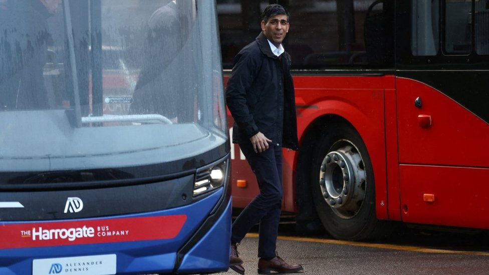 Rishi Sunak walks between two parked buses at the depot in Harrogate