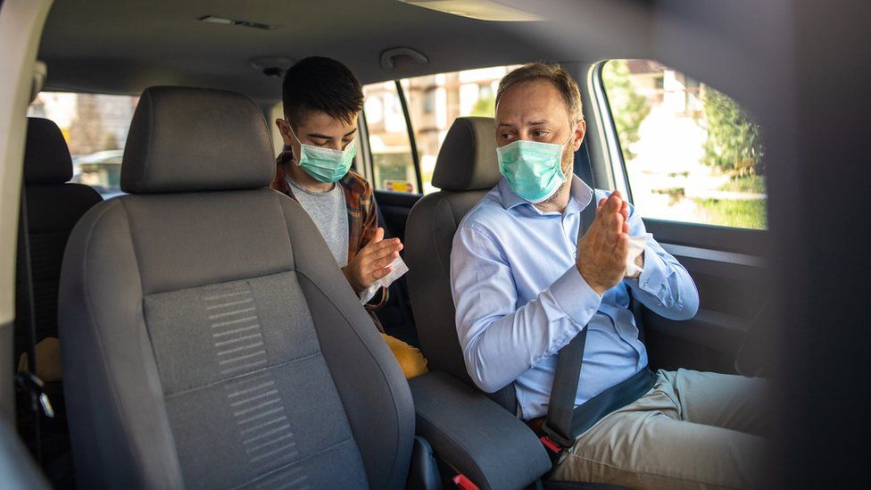 A taxi driver and passenger wearing masks