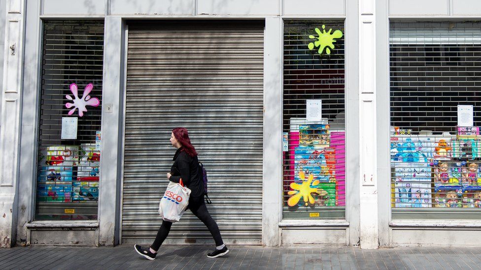 Woman walking in front of shuttered shops