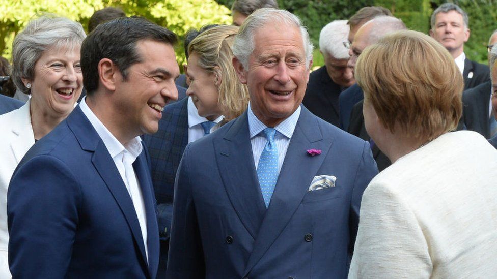 Theresa May (L), Greek Prime Minister Alexis Tsipras (2L) and German Chancellor Angela Merkel speak to Prince Charles (C), in the gardens of St James's Palace in central London following the Western Balkans summit on 10 July 2018