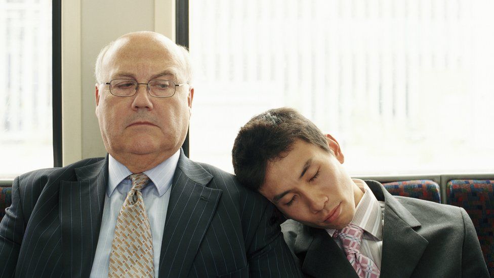 Young man asleep on another man's shoulder