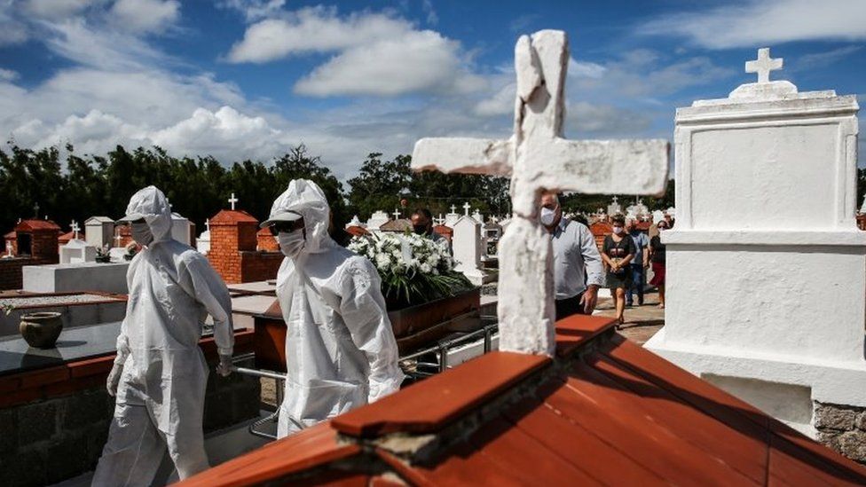 Рабочие в защитном снаряжении тянут гроб во время захоронения 61-летнего Лусио Перейры де Лима, скончавшегося из-за коронавирусной болезни (COVID-19), на кладбище Белем-Ново в Порту-Алегри, Бразилия, 2 апреля 2021 г.