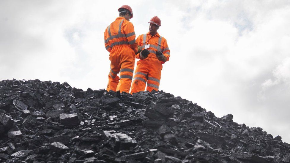 Men standing on a pile of coal