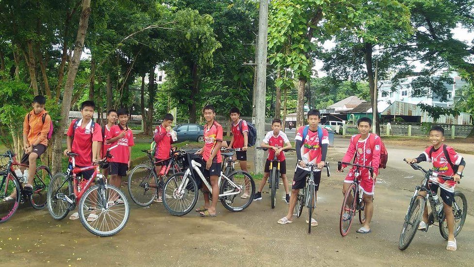 Meninos tailandeses em suas bicicletas pouco antes de entrar na caverna de onde foram resgatados