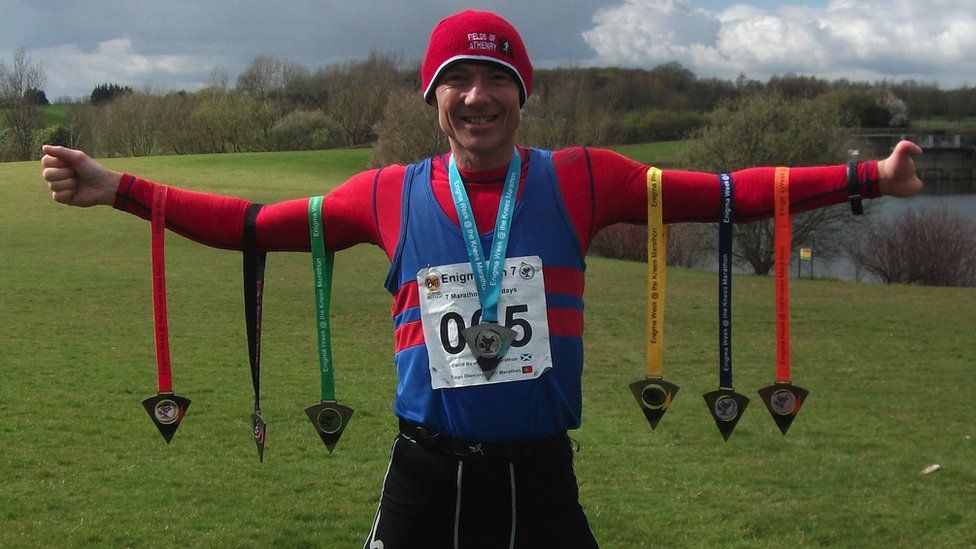 Image of Steve Edwards. Several marathon medals are hung on his arms.