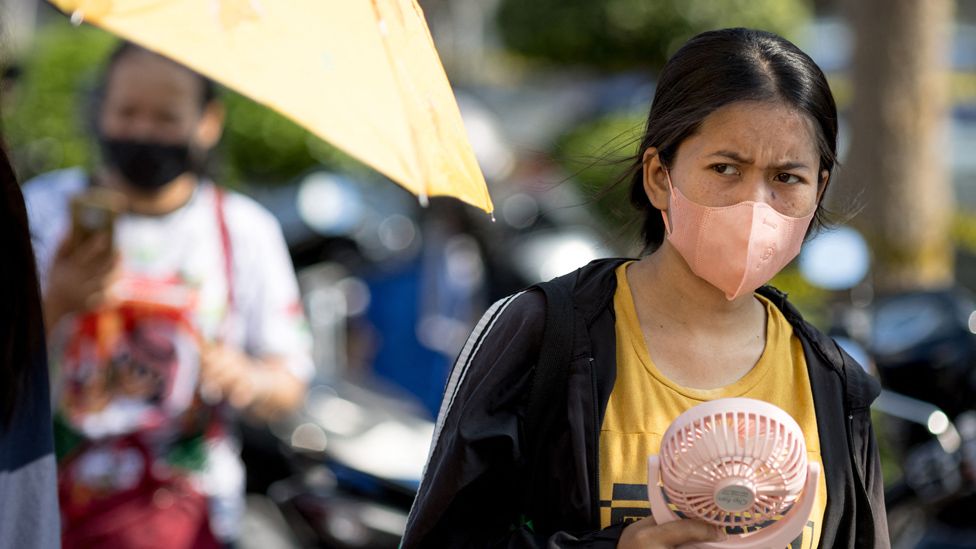 A woman fans herself during hot weather in Bangkok, Thailand
