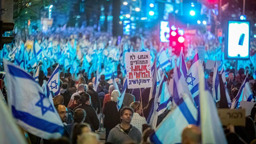 A protester holds a placard that says in Hebrew "We are not donkeys we are the Messiah Democracy" during an anti-reform demonstration.