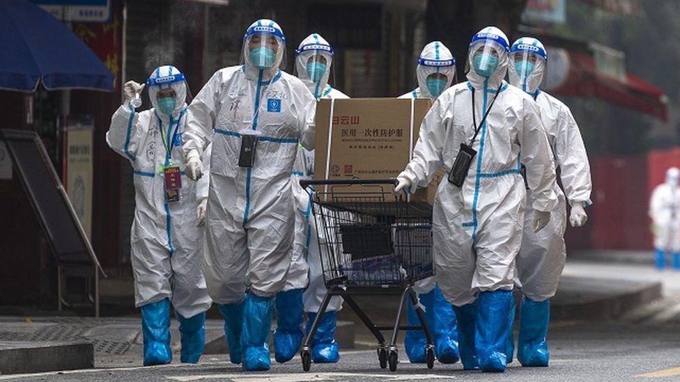 Workers in PPE walk by a residential block under COVID-19 lockdown in Guangzhou in south China's Guangdong province on Thursday, November 10, 2022.