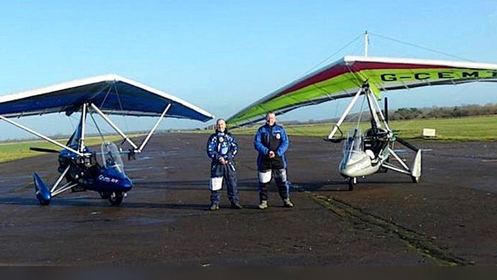 Two men seen standing in front of microlight aircraft