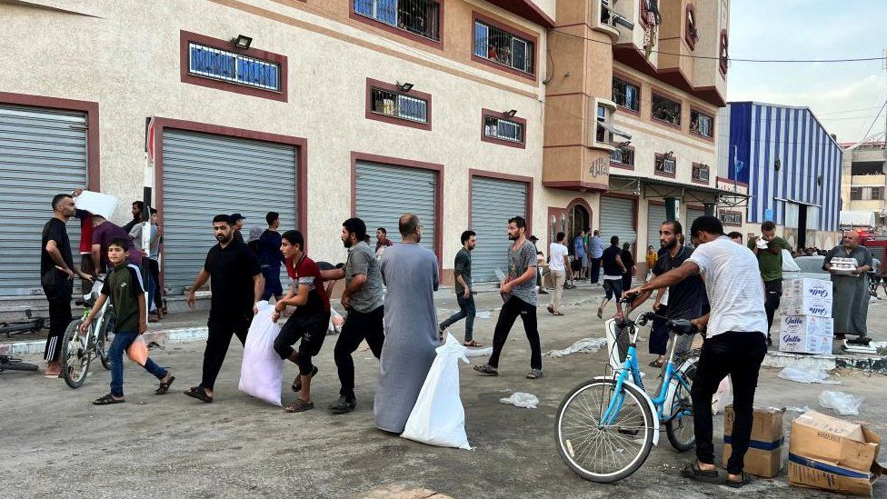 People in Gaza carry food supplies near a UN Palestinian refugee agency-run warehouse in Khan Younis, southern Gaza on 28 October