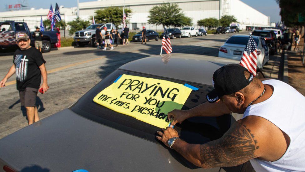 San Tee decorates his car with a President Donald Trump sign during a Pro-Trump car caravan in Long Beach, California on October 3, 2020
