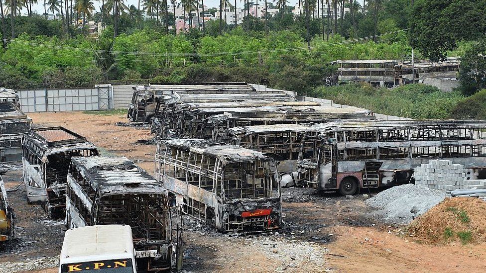 The skeletal remains of several buses belonging to a private travel company are parked in the yard after being set on fire by an angry mob during violence due to the Cauvery water dispute
