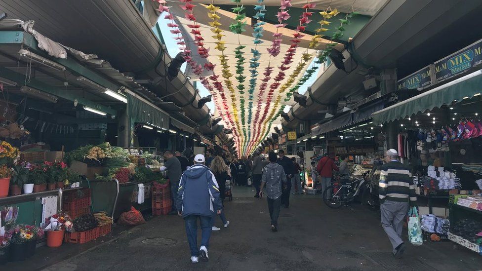 People walk through the market in Tel Aviv