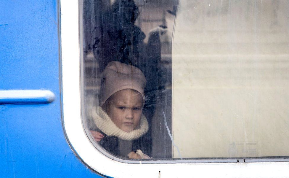 A young girl looks out of a train window before it leaves carrying women and children that fled fighting in Bucha and Irpin from Irpin City to Kyiv, 4 March 2022