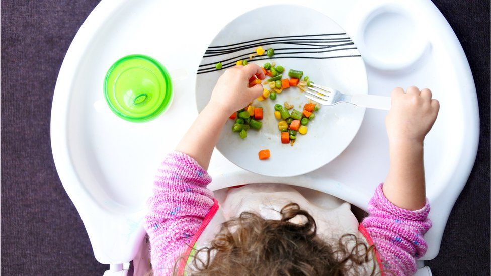 Above view of a little toddler child eats vegetables.