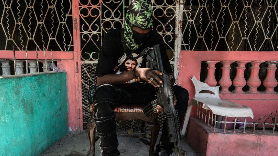 A man sits with a machine gun in Port-au-Prince