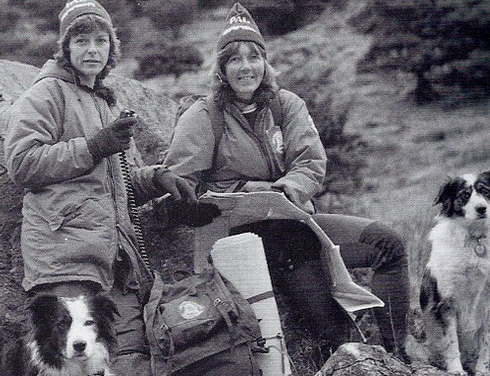 Old black and white picture of two women and two collies