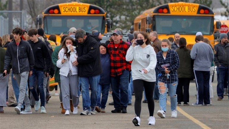 Parents walk away with their kids after the shooting at Oxford High School in Oxford, Michigan