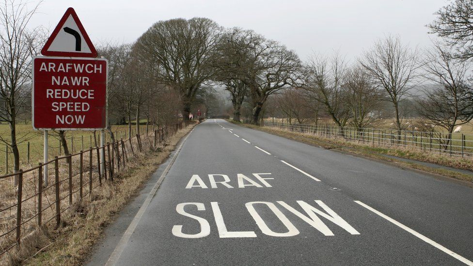 picture of a road with a welsh slow down sign