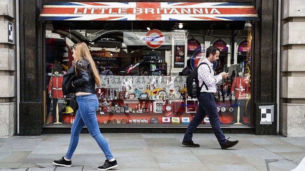 Pedestrians walk past a souvenir shop displaying United Kingdom themed merchandise in central London.