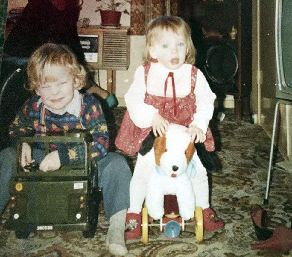 Family photo of young Terri on a toy dog on wheels