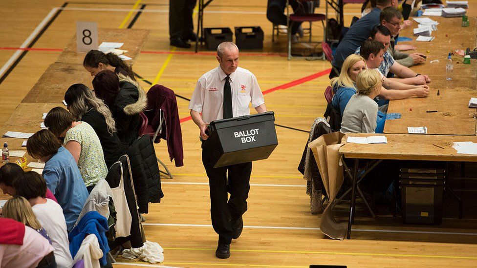 An official carries a ballot box at a count