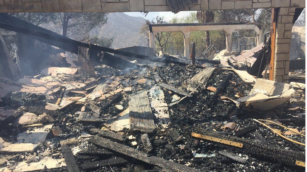 Remains of a burned home smoulder in Iron Canyon Road area near Santa Clarita on Sunday, July 24, 2016