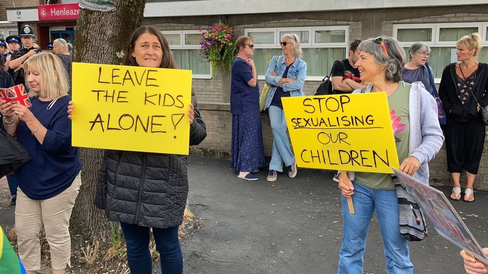 Protestors carrying signs reading 'leave the kids alone'