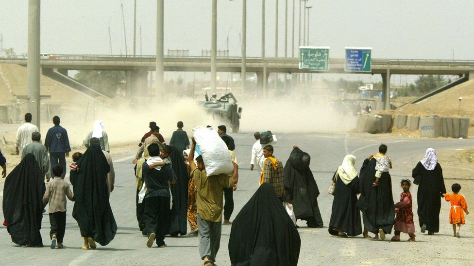 Displaced Iraqis from the city of Falluja walk back home 28 April 2004