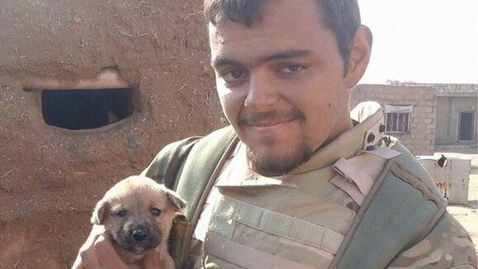 Aiden Aslin is seen wearing military uniform and holding a puppy