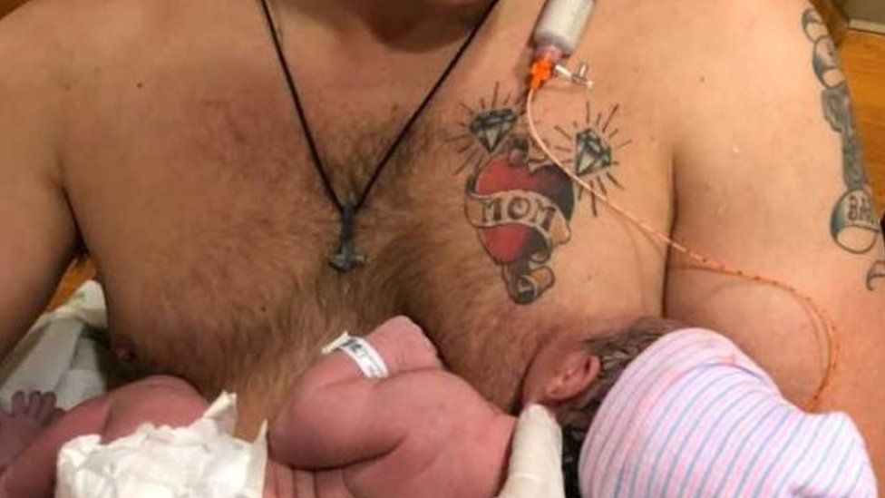 Dad breastfeeds newborn daughter