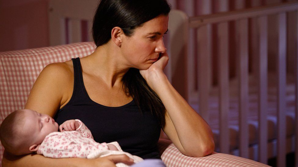 worried looking woman holding baby