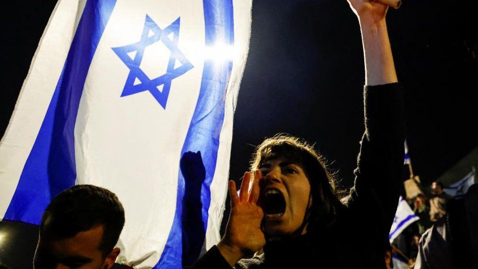 Женщина кричит, держа израильский флаг